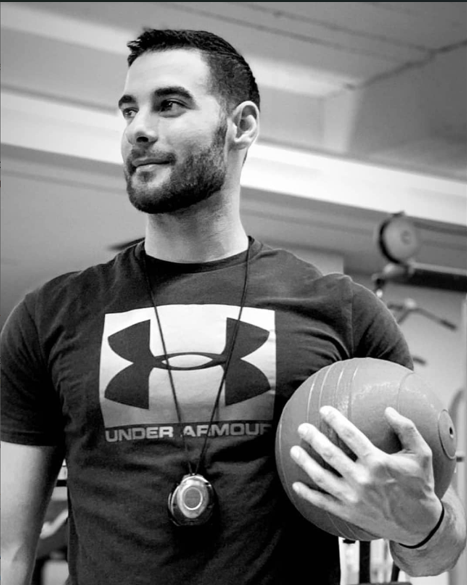 Photo of the personal trainer Apostolis Kontotasios holging a training ball and having a timer on his neck